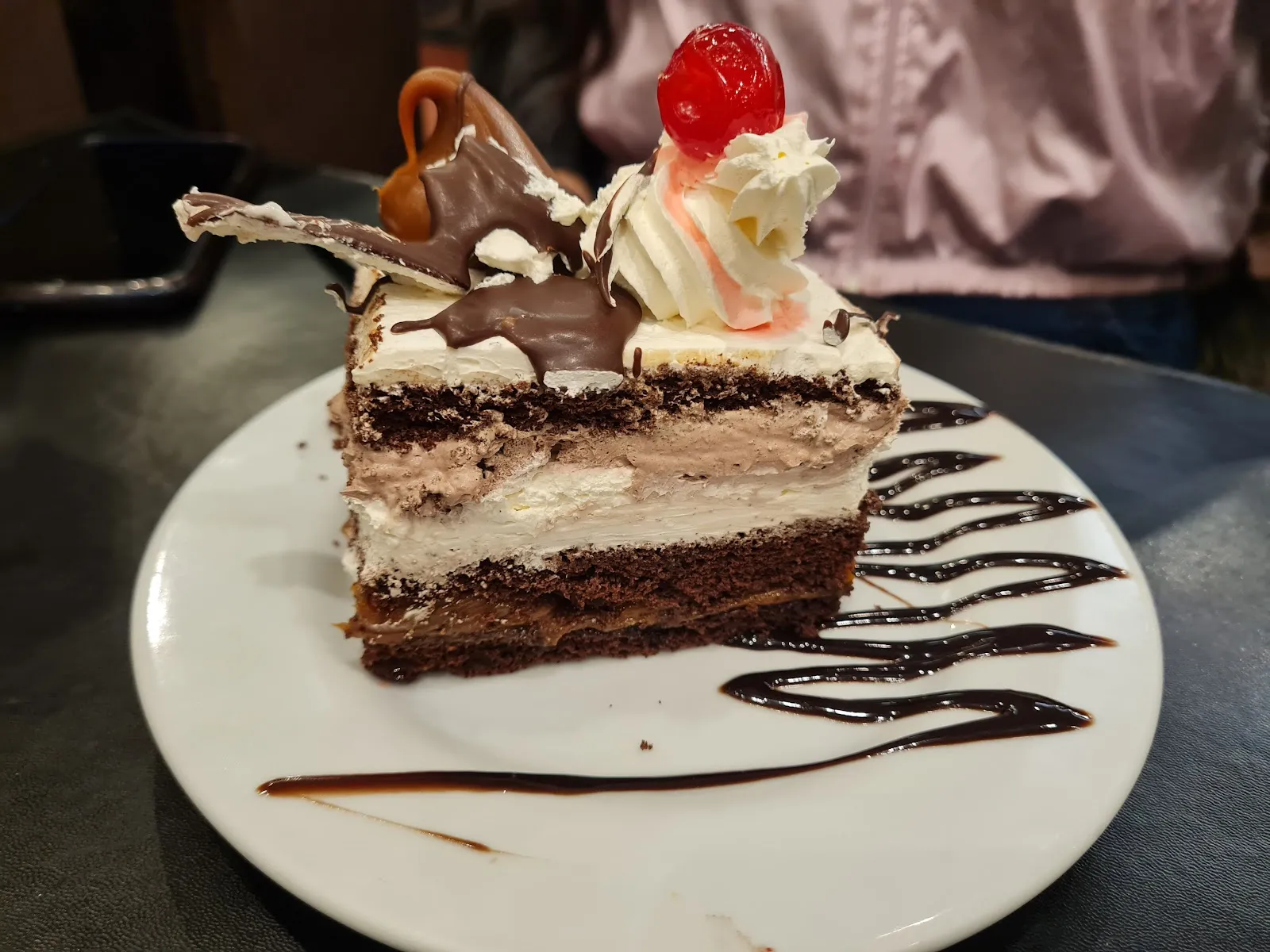 Porción de torta de chocolate con crema y cereza